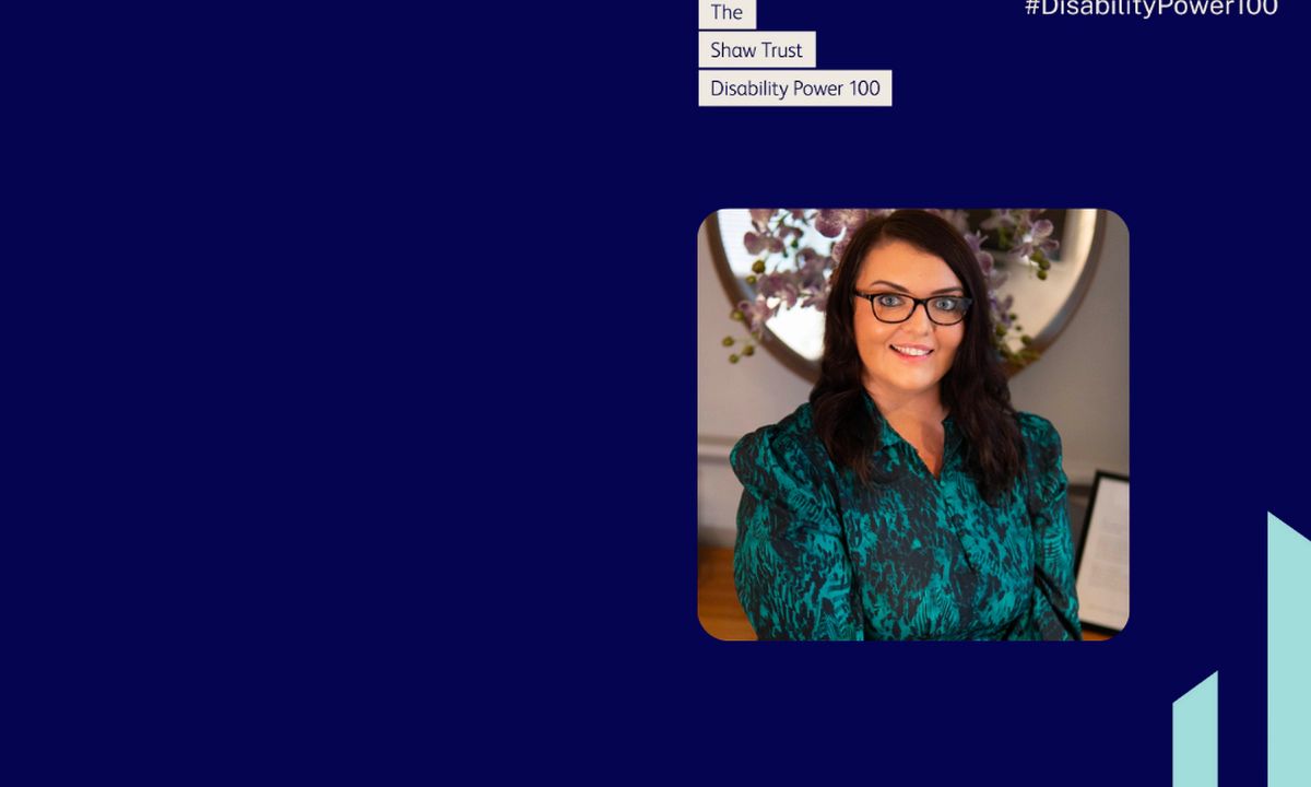 Photo of Emma Partlow, a white woman with long dark brown hair, brown glasses and a blue patterned dress. Emma is smiling in front of purple orchids. Above the photo text reads "The Shaw Trust Disability Power 100" in blue font in cream boxes, with the Disability Power 100 hashtag top right and two teal Transreport pillars bottom right. Navy blue background with cream text.