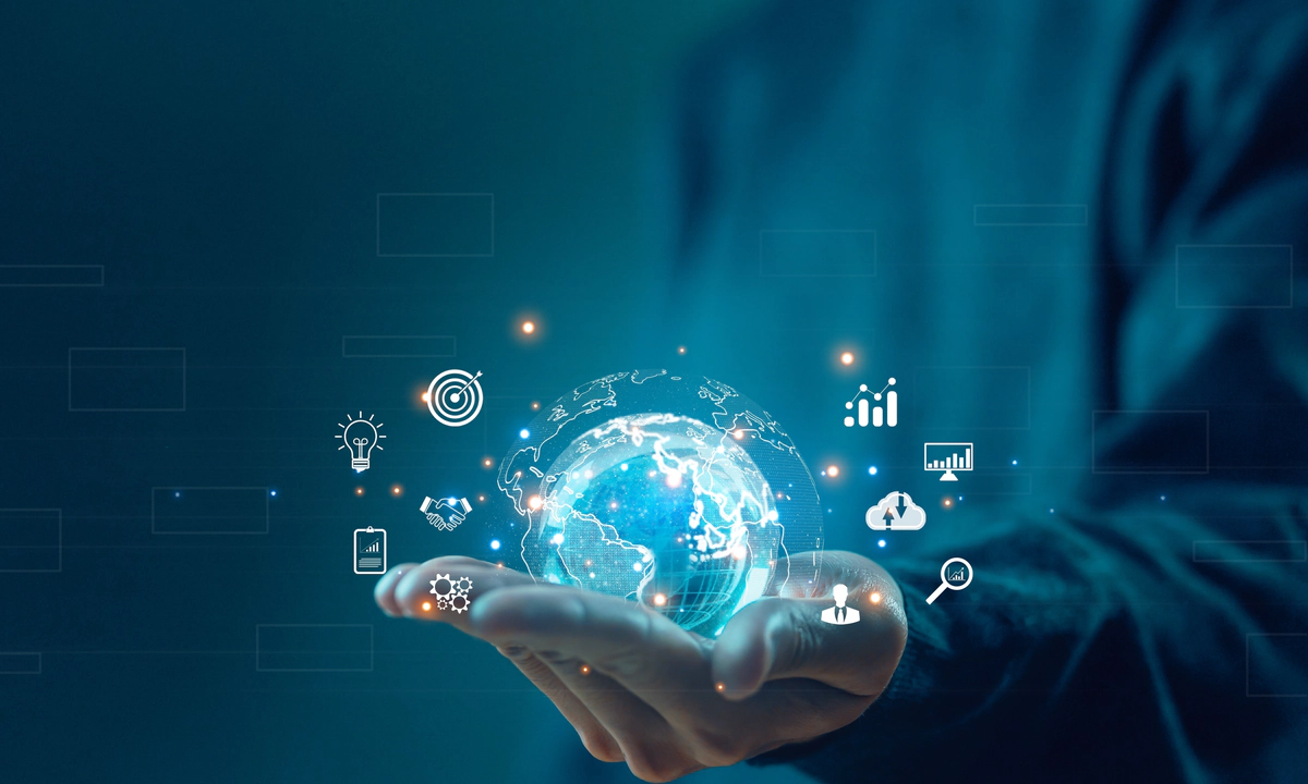 the image is a photo of a person in a blue jumper, holding out their hand palm upwards. Inside their palm is a graphic of a globe surrounded by different icons including an illustrated white lightbulb, a dartboard with a dart in the bullseye, a magnifying glass, and various graphs and charts. White Transreport logo in the top left corner, 4 pillars with Transreport to their right.