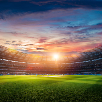 A photo of a sports stadium with bright green grass, players on the pitch, and an open sky above.