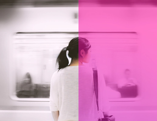 A woman standing on a platform facing a moving train.