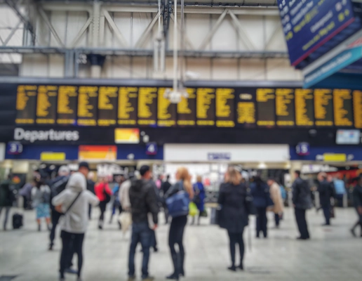 Blurred image of crowded passengers in Waterloo looking at the timetable.