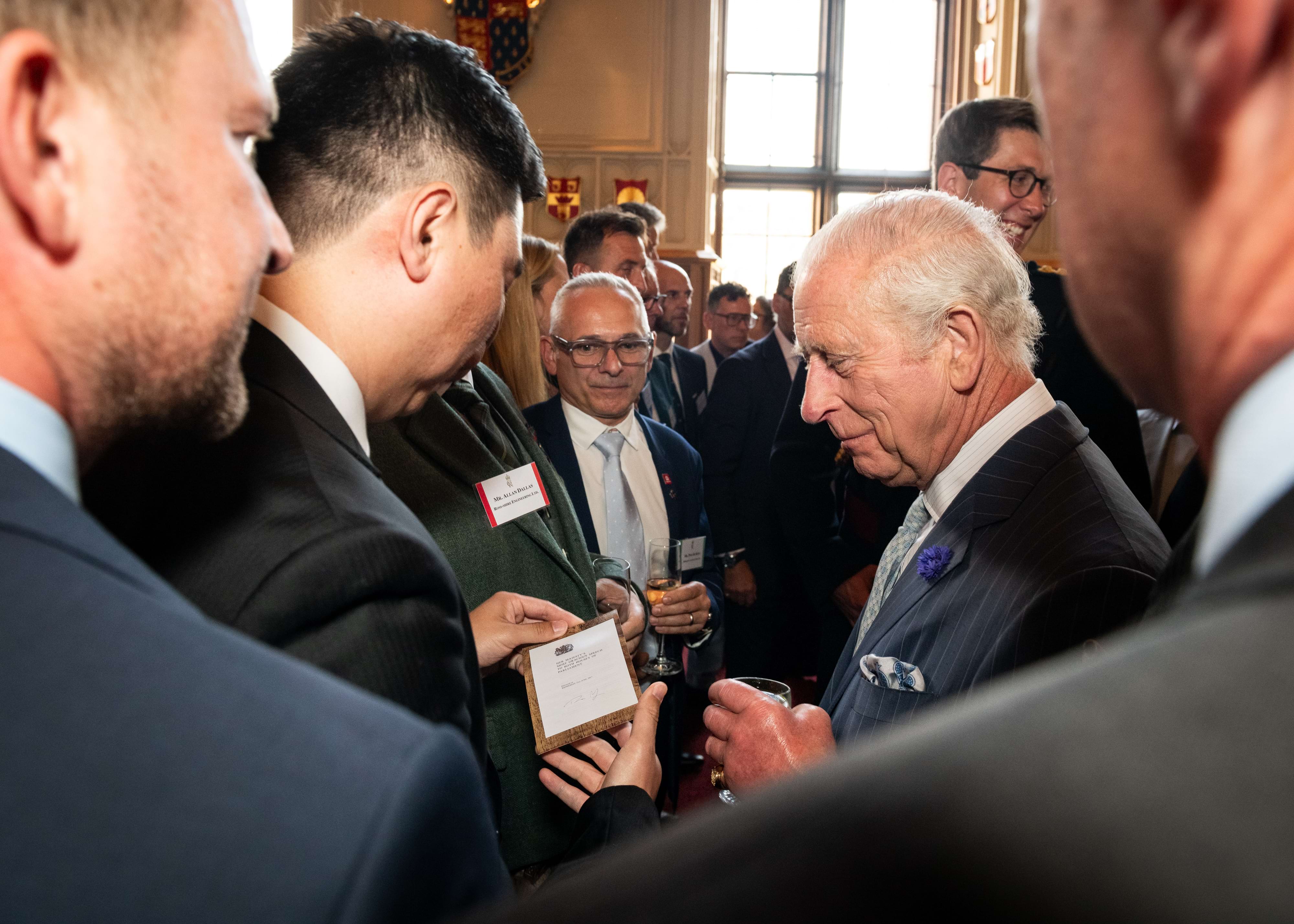 Jay Shen with King Charles III. Jay is showing the King a picture of the Queen’s Speech from her parliament and the King is smiling.