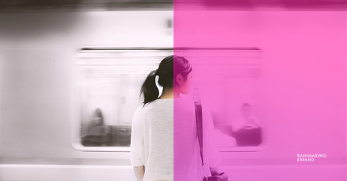 A woman standing on a platform facing a moving train.
