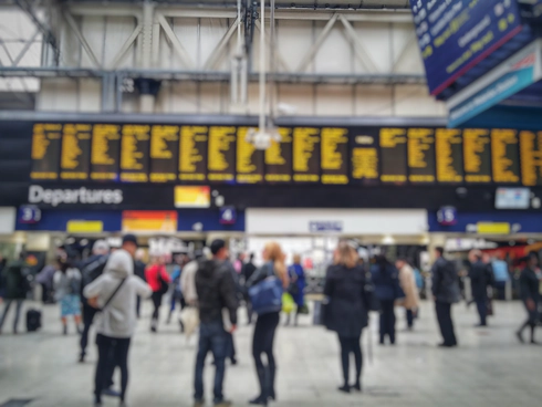 Blurred image of crowded passengers in Waterloo looking at the timetable.