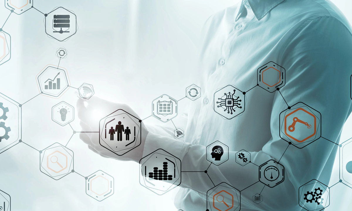 The torso of a man wearing a button-up shirt holding a mobile phone, with an interconnected matrix of various process icons overlayed on top.