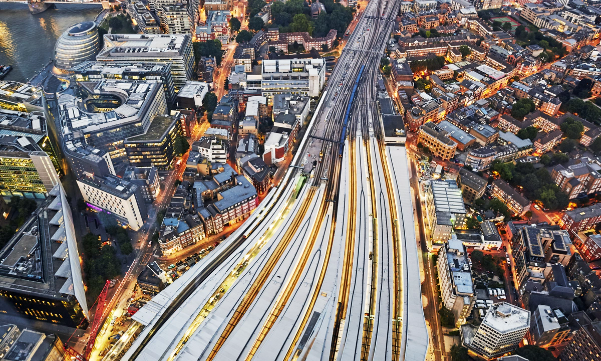 An aerial view of several trains on converging train tracks in a big city with skyscrapers. An aerial view of several trains on converging train tracks in a big city with skyscrapers.